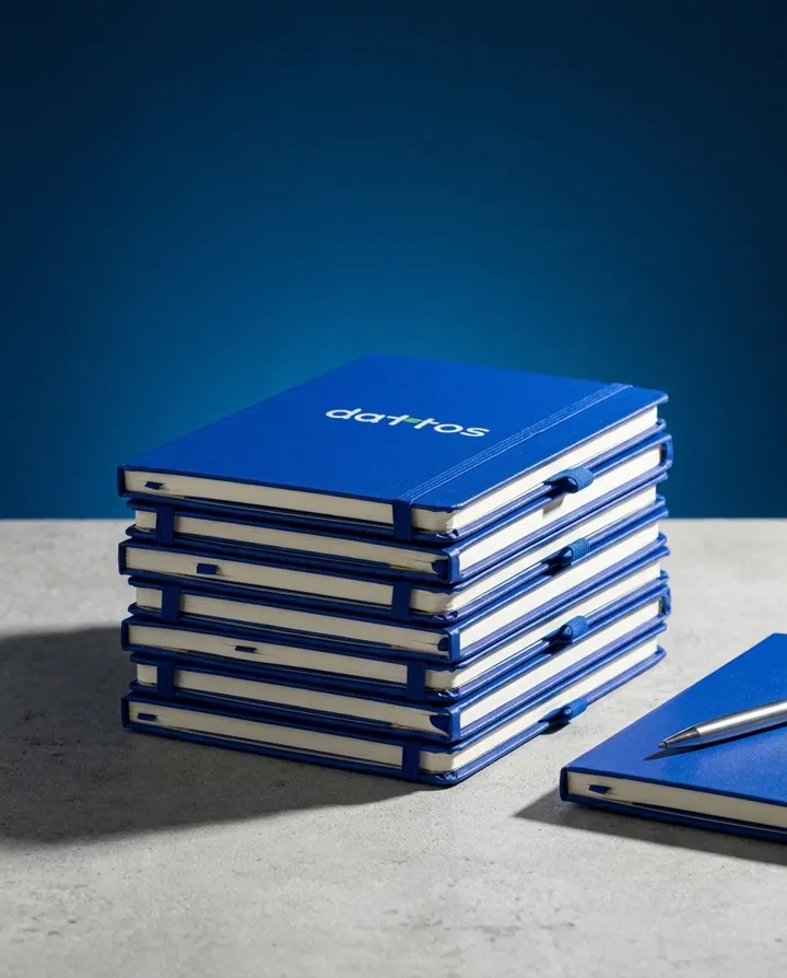 Pilha de cadernos azuis tipo moleskine com logo da Dattos